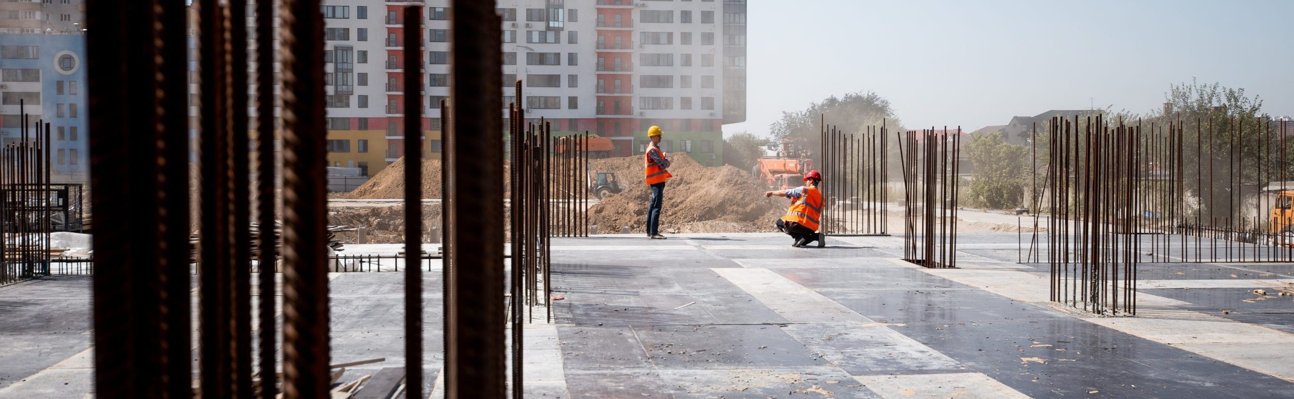 The building site against the background of a multistorey building. Two builders are working .